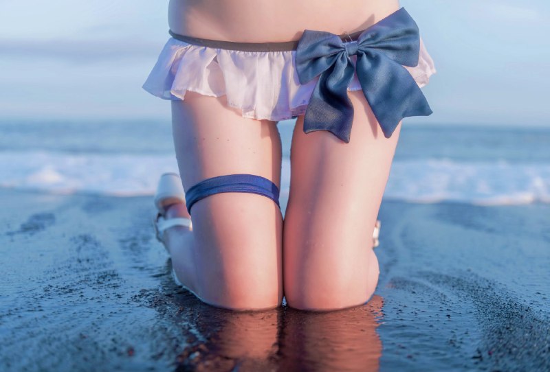穿着白色裙子和蓝色弓的女人坐在海滩上