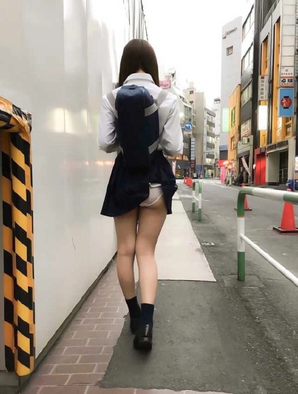 一位穿着蓝色裙子和白色内衣的女人走在街上