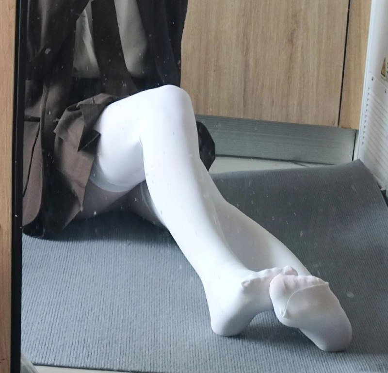 穿着白色袜子和棕色外套的女人坐在地板上