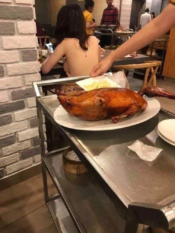 女人坐在一张桌子上,她面前有一盘食物