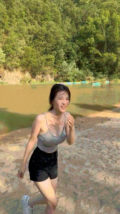 一位穿着灰色坦克顶和黑色短裤的女人在海滩上散步