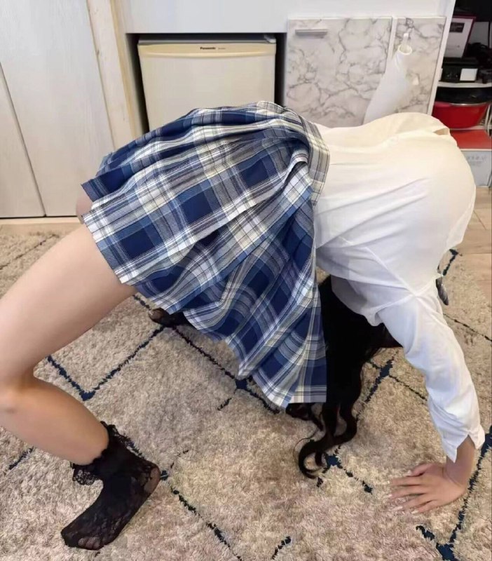 穿着蓝色和白色的裙的女孩在地毯上做手掌