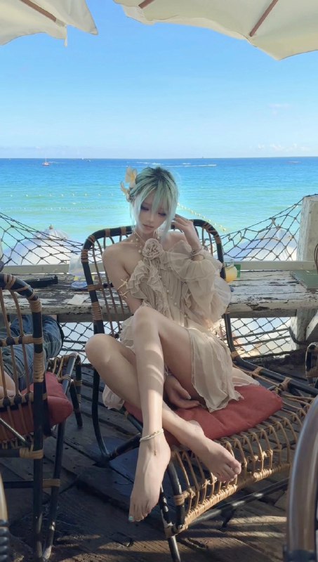 一位穿着白色衣服的女人坐在一把椅子上,俯瞰大海