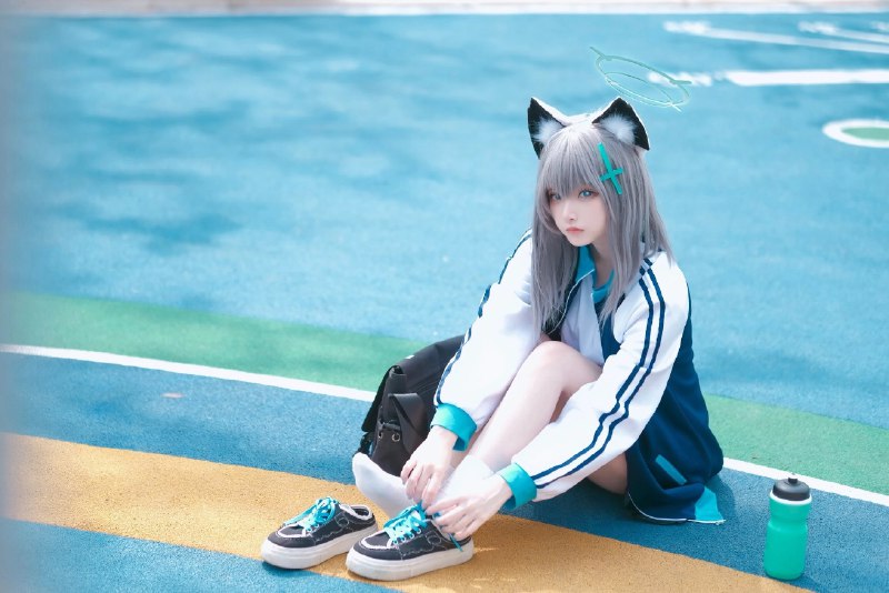 戴着猫类的帽子和蓝色夹克的女人坐在地上