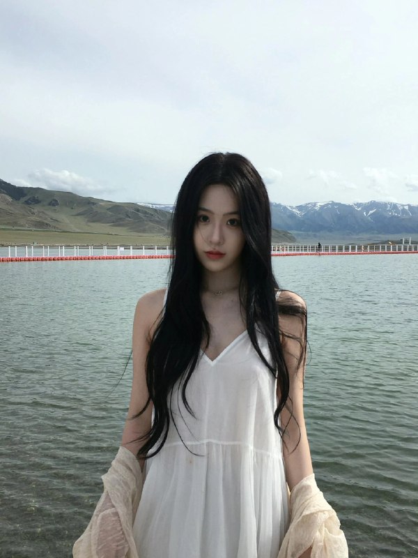 长黑头发的女人站在一个水体旁边