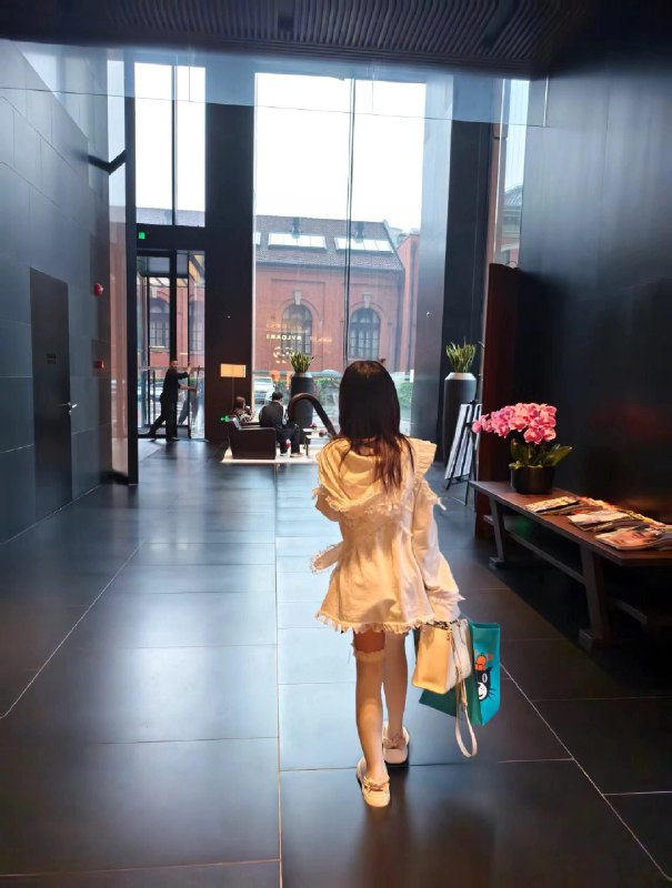 一位穿着白色衣服的女人走在走廊上