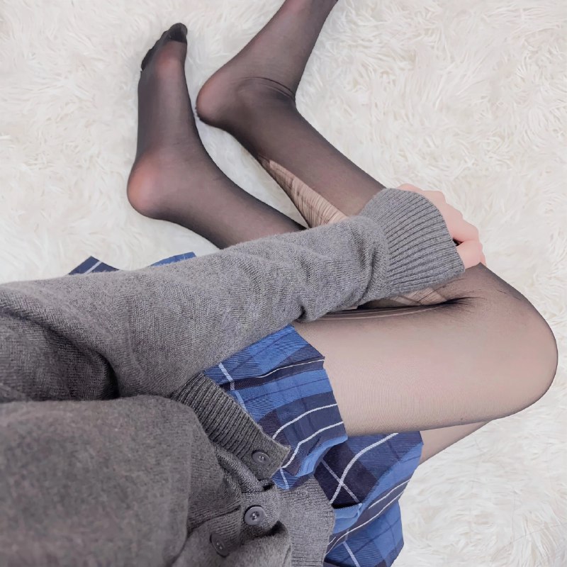 穿着灰色衬衫和黑色衬衫的女人坐在白色地毯上