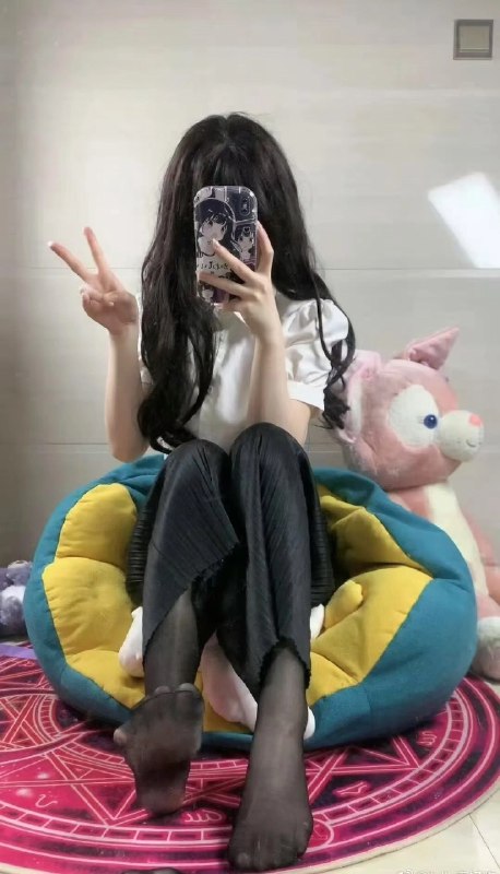 一位女孩坐在椅子上,拿着一张手机,上面有一只猫的照片