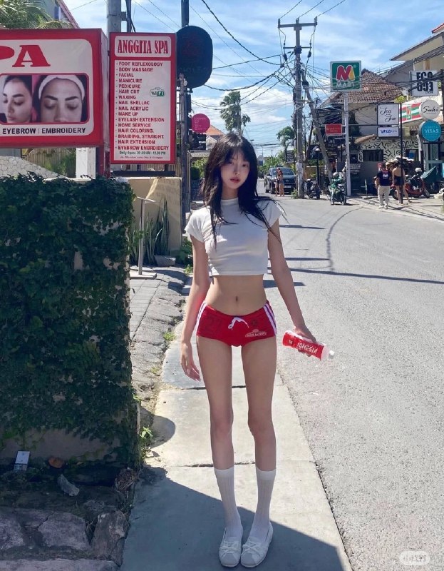 一位穿着白色衬衫和红色短裤的女人站在走廊上