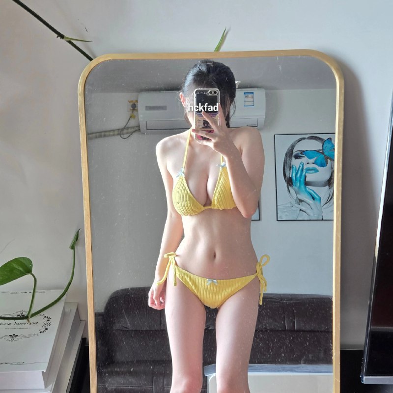 穿着黄色比基尼的女人在镜子前拍个自拍