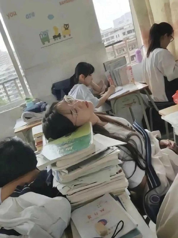 戴眼镜的女孩睡在一堆书上