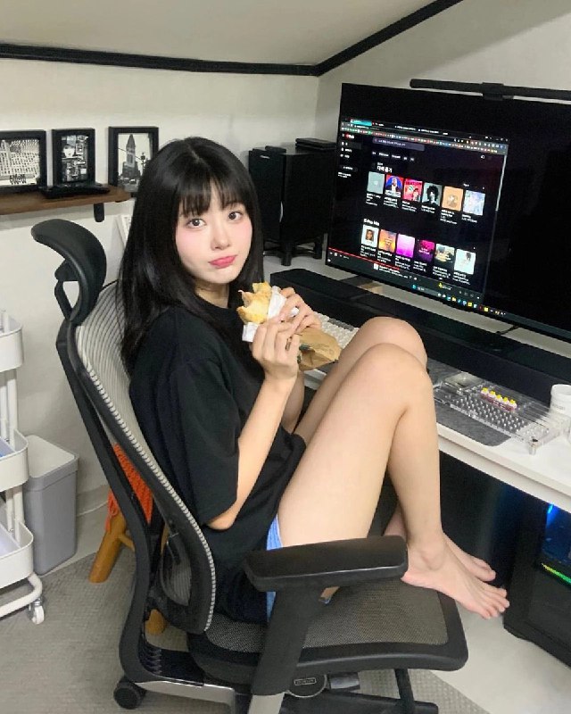 女人在电脑前坐在椅子上吃一顿三明治