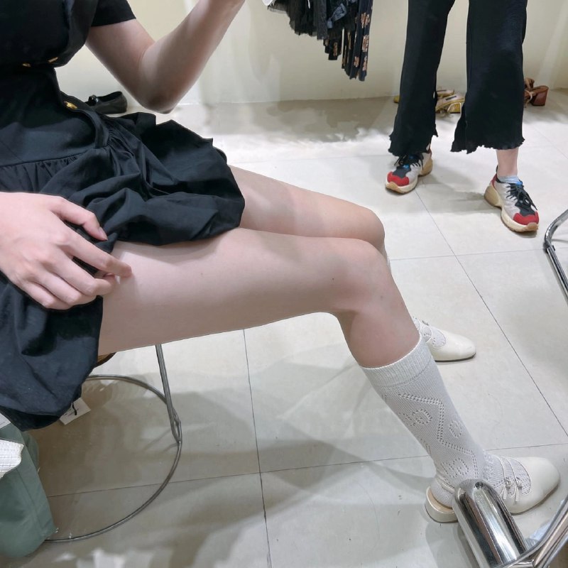 女人坐在椅子上,穿着白色袜子和黑色裙子