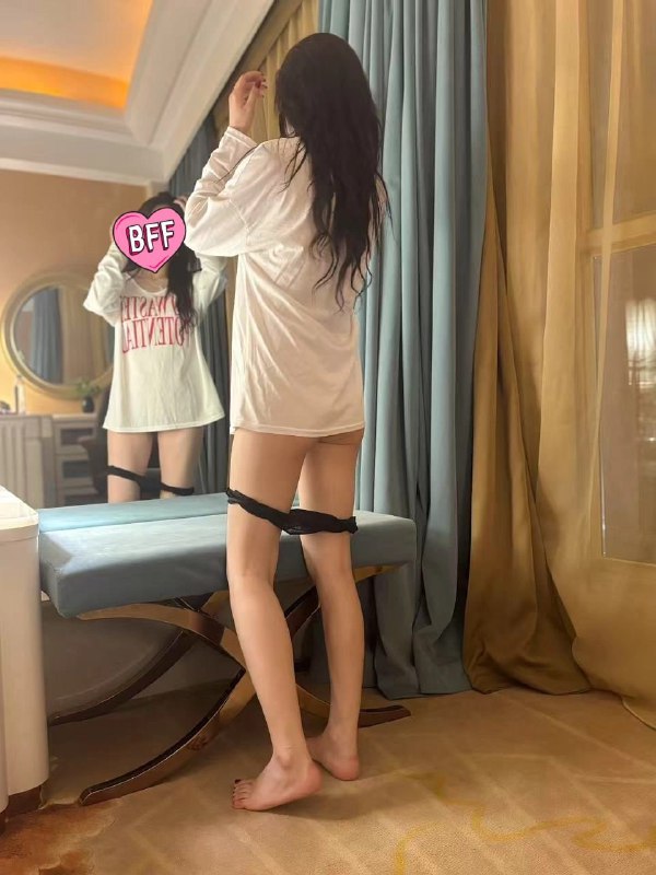 一位穿着白色衬衫和黑色内衣的女人站在镜子前