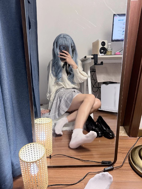 一位穿着白色衬衫和黑色衬衫的女人在镜子前拍自拍