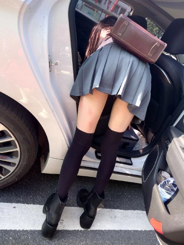 穿着灰色裙子和黑色靴子的女人正在车上