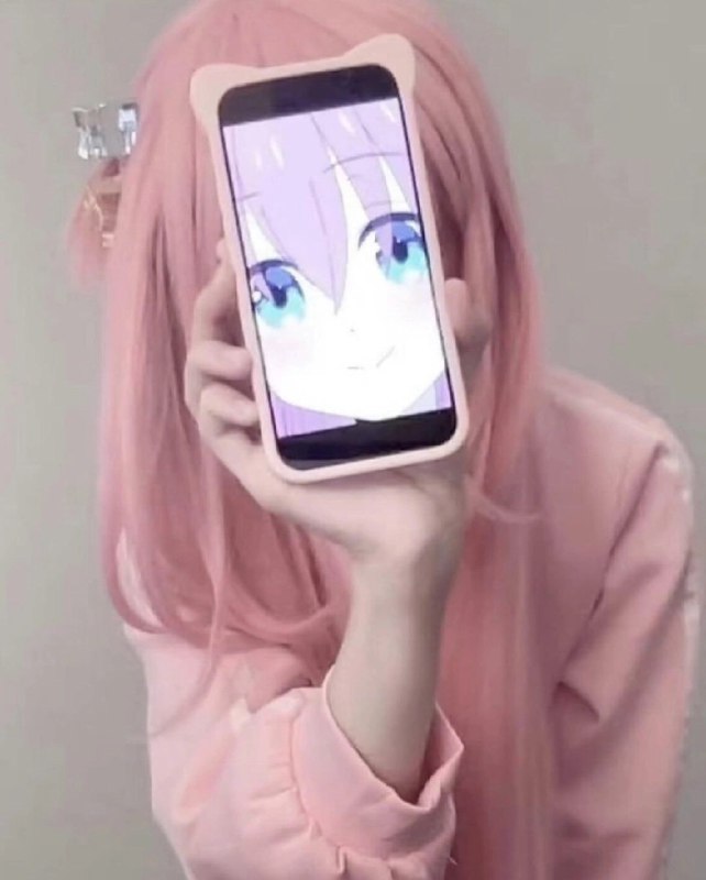 粉红发的女孩拿着手机,上面有一张卡通脸