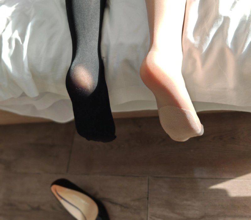 一双黑色袜子和一双粉红色的袜子在床上