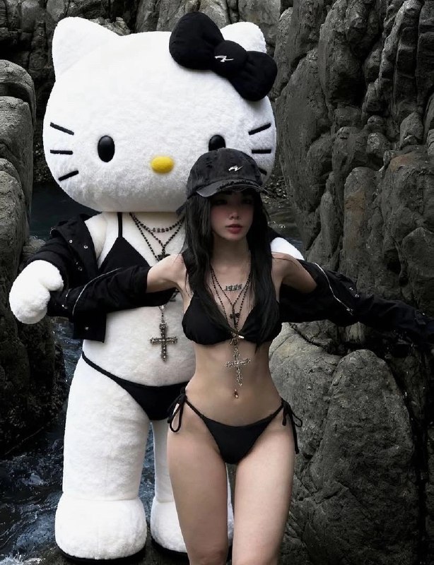 穿着比基尼的女人站在一个Hello Kitty娃娃旁边