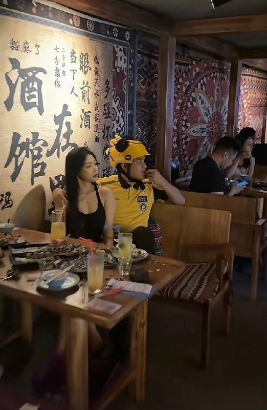 穿着黄头盔的男人坐在一家餐厅的女人旁边